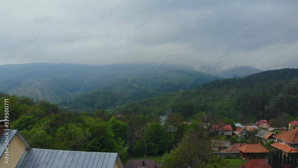 It peaceful morning in mountains with forest and fog looming over village in distance It peaceful morning in mountains with forest and fog looming over village in distance