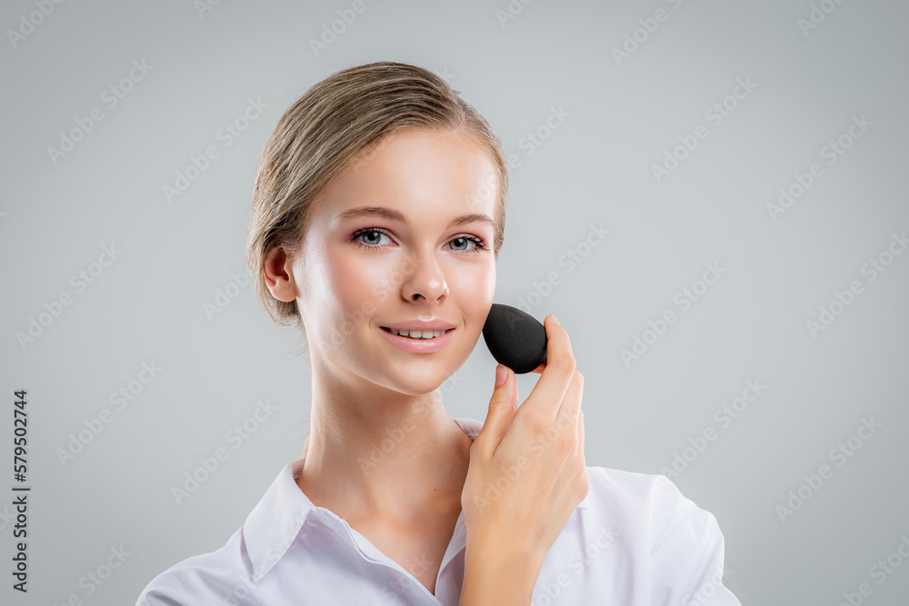 Cute beautiful natural brunette girl cleaning face with cotton sponge smiling looking at camera over white background. Cosmetology and spa. Cute beautiful natural brunette girl cleaning face with cotton sponge smiling looking at camera over white background. Cosmetology and spa.