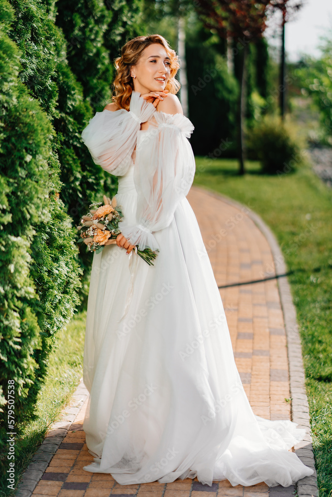 beautiful bride in a white delicate dress on the path in the park.