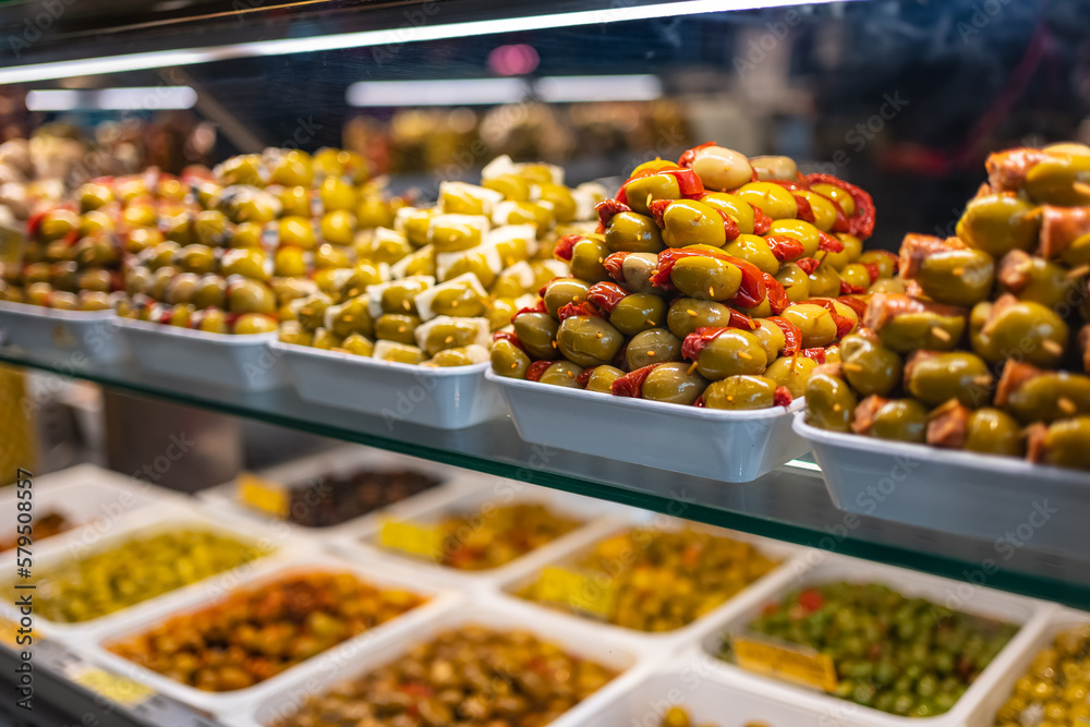 Counter of a market with piles of food, olives and pickles in a colorful exhibition, Mercado San Miguel, Madrid.
