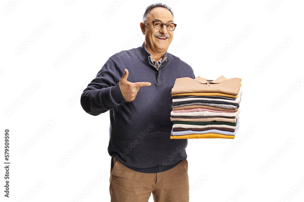 Cheerful mature man holding a pile of folded clothes and pointing Cheerful mature man holding a pile of folded clothes and pointing