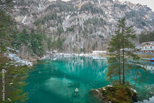 Fototapeta Naklejka Na Ścianę i Meble -  Small lake of turquoise waters in a snowy environment, known as Blausee lake in Switzerland.