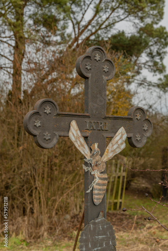 Crucifix near trees and bee house with bee on cross photo