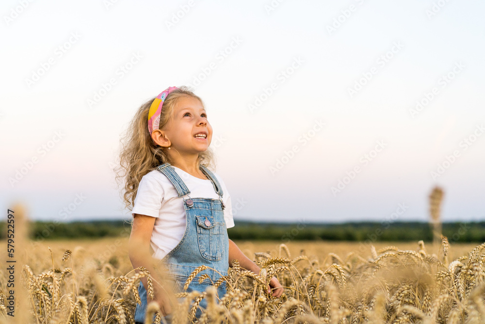 a little blonde curly girl running in a wheat field, the concept of human freedom a little blonde curly girl running in a wheat field, the concept of human freedom