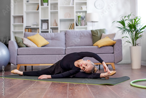 Little girl practicing stretching in room. Physical exercises for children at home. Concept of sport