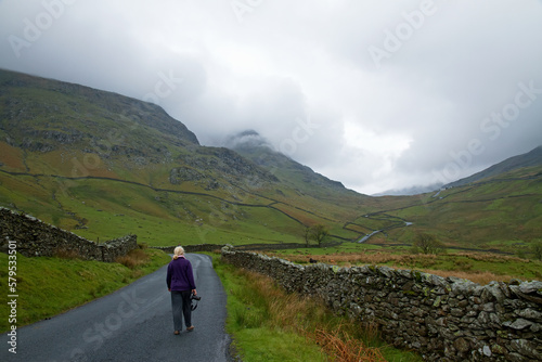 Blonde woman walking down a road in the Lakes District in England