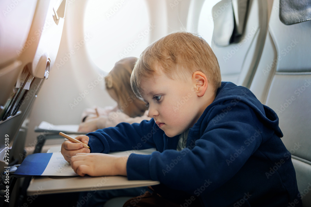 kids fly in airplane and draws with pencil in coloring book. travel with children kids fly in airplane and draws with pencil in coloring book. travel with children