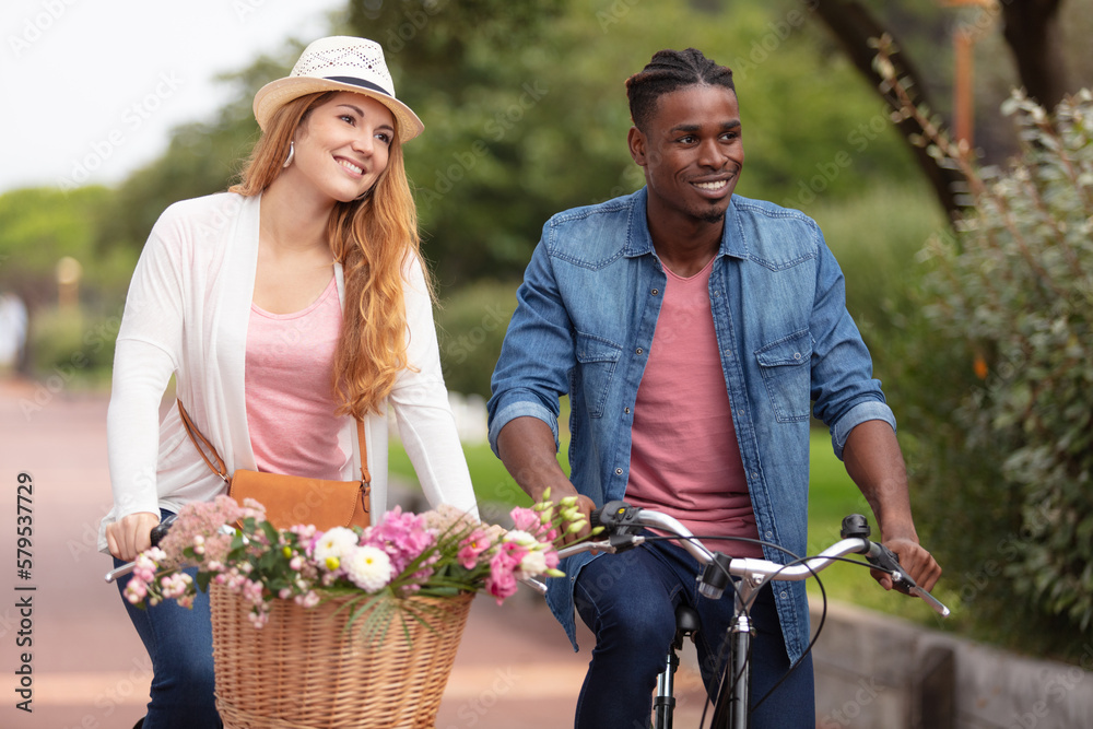 Obraz premium young couple riding bike in park taking flowers home