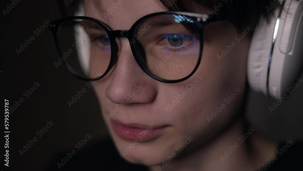 macro side view of focused man wears glasses is looking at light from the dark. Male uses pc screen, internet, TV, smartphone. Reading, watching, working online late. Copy space. macro side view of focused man wears glasses is looking at light from the dark. Male uses pc screen, internet, TV, smartphone. Reading, watching, working online late. Copy space.