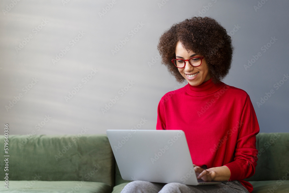Smiling woman freelancer, copywriter typing on keyboard, using laptop working online from home. Stylish businesswoman wearing red eyeglasses planning startup in modern office. Successful business Smiling woman freelancer, copywriter typing on keyboard, using laptop working online from home. Stylish businesswoman wearing red eyeglasses planning startup in modern office. Successful business