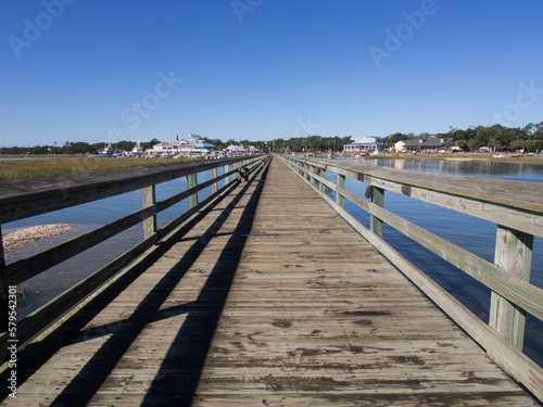 The long wooden pier looking inwards at at Murrell s Inlet  south of Myrtle Beach  South Carolina  USA  on a sunny day with blue sky.