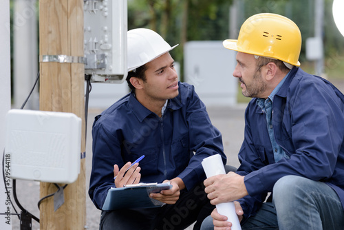 two male technicians in discussion while reading outdoor meter