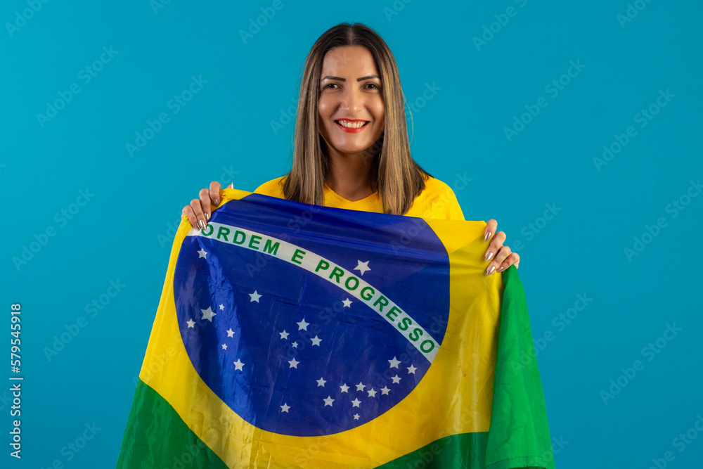 Brazilian female supporter, wearing shirt and Brazilian flag. Brazilian soccer fan in studio