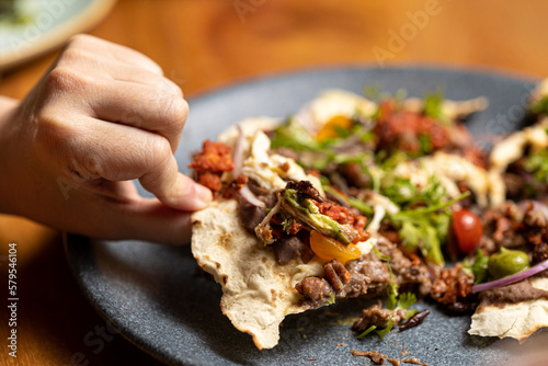 Mexican dish tlayuda, held with one hand, about to be eaten. photo