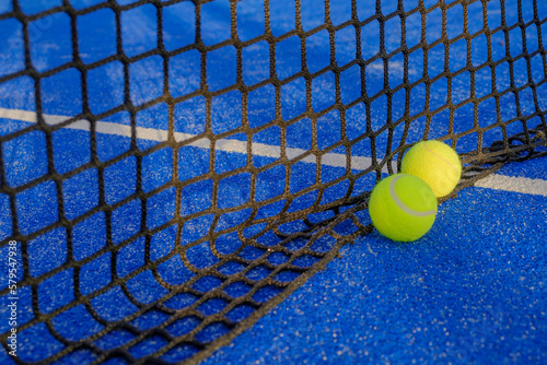 Two paddle tennis ball near the net of a blue court © Vic