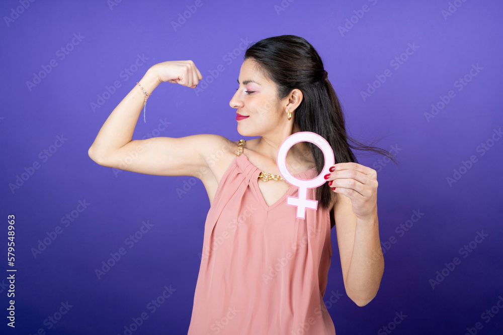 strong woman holding feminist symbol in her hand on isolated purple velvet background strong woman holding feminist symbol in her hand on isolated purple velvet background