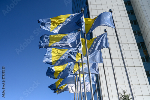 State flags of Bosnia and Herzegovina waving on the wind. Bosnia Herzegovina national flag blowing on flagpole in front of Parliament in Sarajevo. 