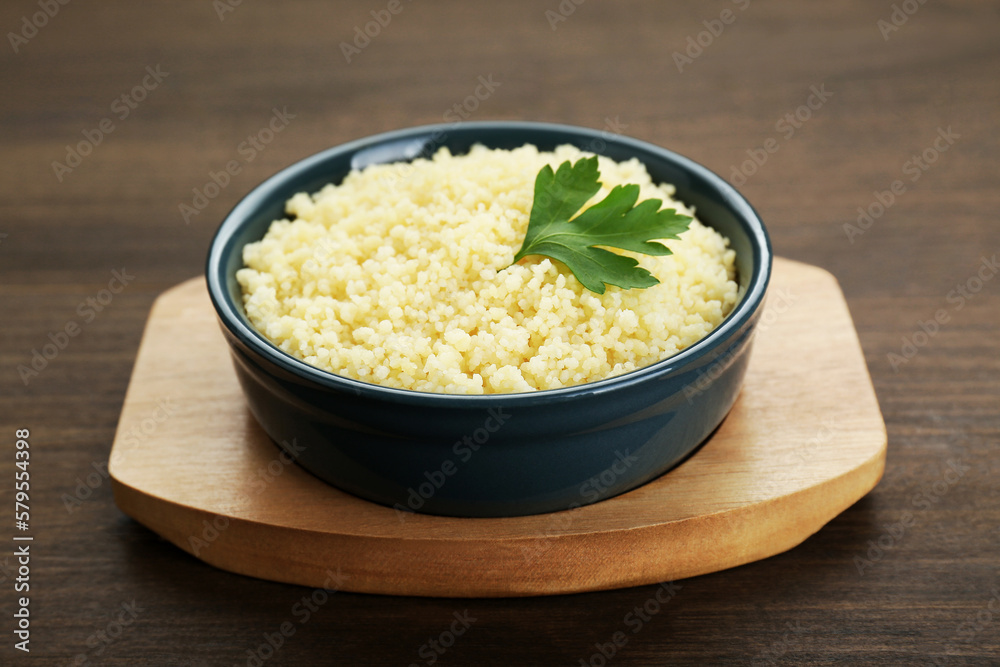 Tasty couscous with parsley on wooden table, closeup Tasty couscous with parsley on wooden table, closeup