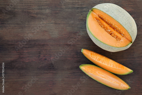 Cut delicious ripe melon on wooden table, flat lay. Space for text
