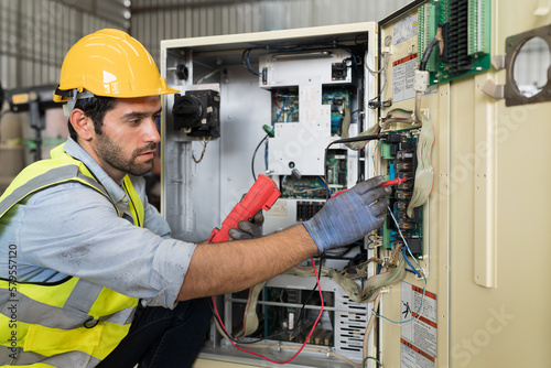 Male electrician worker checking, repair, maintenance operation electric system in factory. Male electrician using electrical meters working with operation electric system in workshop