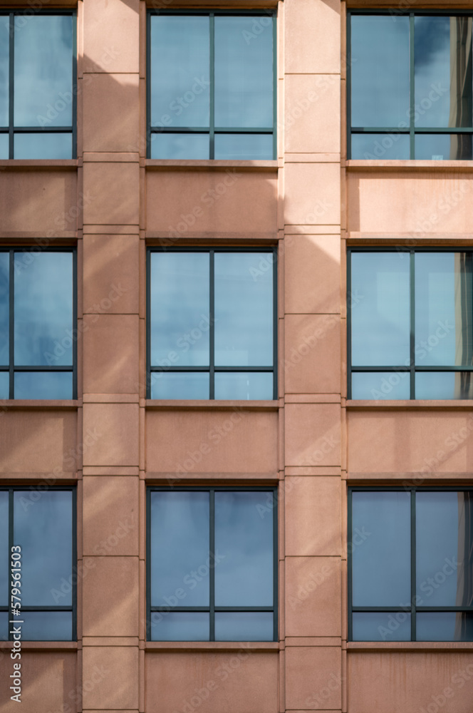 Tan Stone Building Wall with Blue Reflecting Windows.