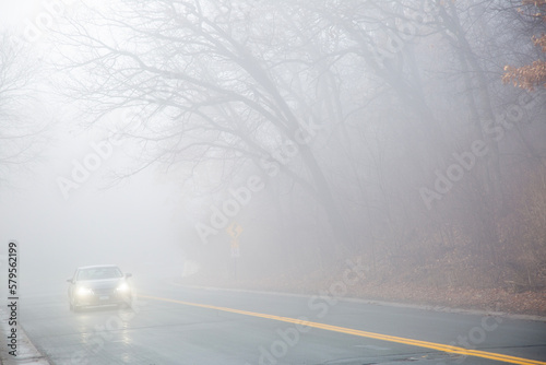 Thick fog with a car driving carefully along a curvy road near Minneapolis Minnesota photo