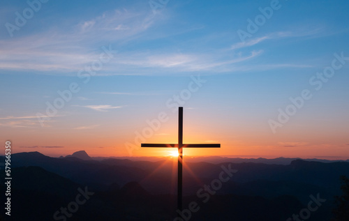 Silhouette of a Christian cross with sunset light in the background symbolizing faith, forgiveness, salvation resurrection of Jesus Christ.
