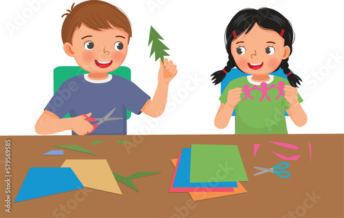 Cute little kids boy and girl cutting colored paper with scissors making paper cut art craft