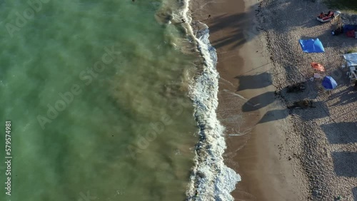 Rising bird's eye drone shot of Penha beach coastline near the capital city of Joao Pessoa in Paraiba, Brazil with waves crashing into the sand and people playing in the water and relaxing. photo