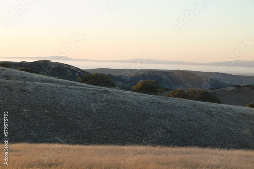 Beyond the golden grasses of summer lie views of Salinas valley and Monterey Bay in Central California photo