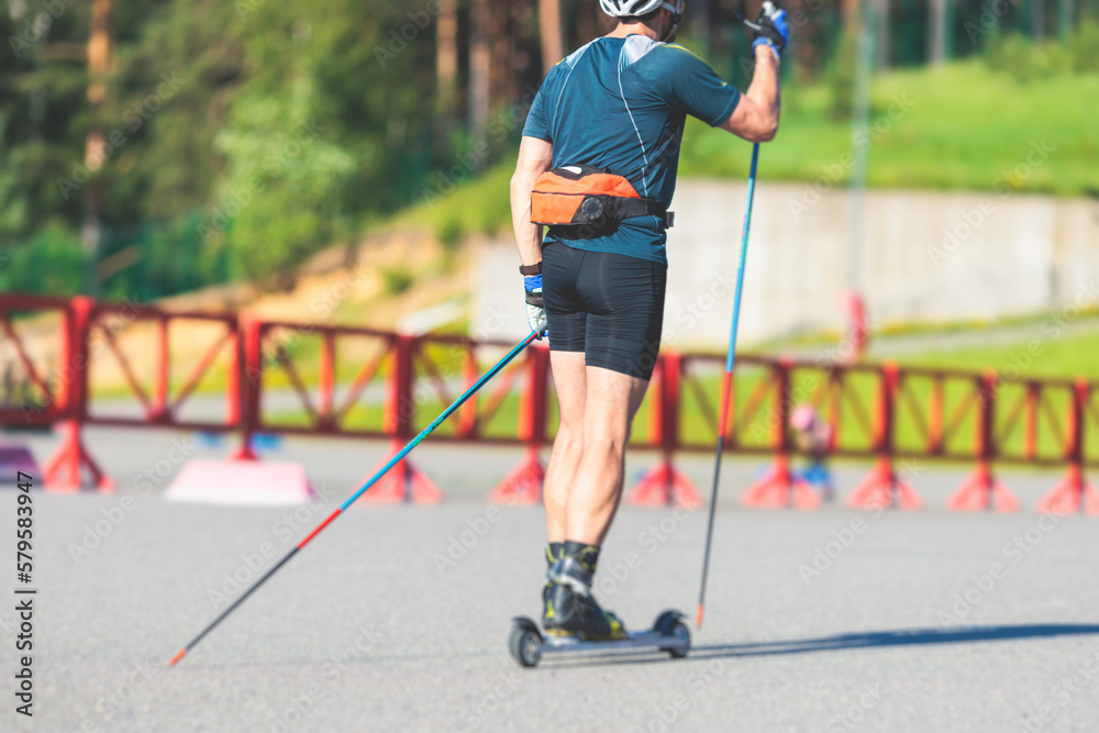 Athletes ride roller skis on asphalt track, group of ski rollers in helmet, cross-country skiing with roller ski in summer sunny day, sportsmen ski-rollers riding, biathlete training Athletes ride roller skis on asphalt track, group of ski rollers in helmet, cross-country skiing with roller ski in summer sunny day, sportsmen ski-rollers riding, biathlete training