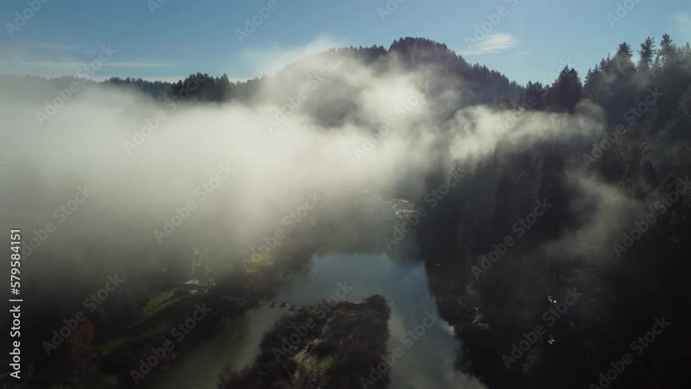 Aerial: Flying through low clouds over river and small town Aerial: Flying through low clouds over river and small town