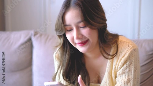 smile asian women sit on sofa in livingroom looking smartphone and celebrate