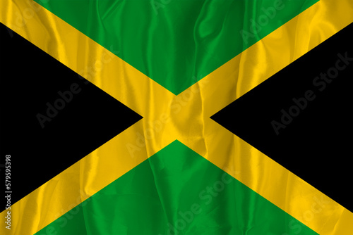 The flag of Jamaica on a silk background is a great national symbol. Texture of fabrics The official state symbol of the country