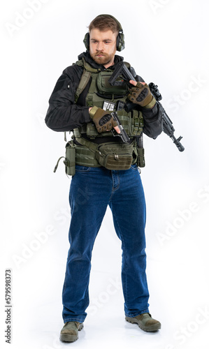 soldier, airsoft player in full gear with a machine gun. a man in headphones, a bulletproof vest, with a backpack and a full-length belt. White background.