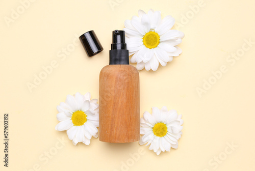 Bottle pf cosmetic product with chamomile flowers on color background