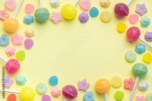 Sweet lollipops and candies on yellow background