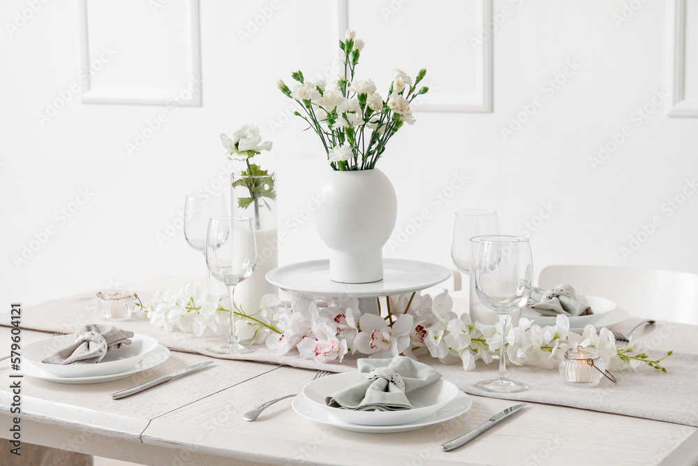 Beautiful table setting for International Women's Day celebration with eustoma and orchid flowers in light room Beautiful table setting for International Women's Day celebration with eustoma and orchid flowers in light room
