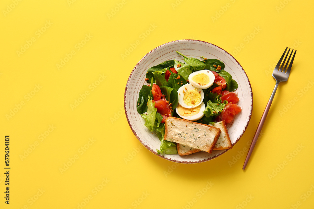 Plate of delicious salad with boiled eggs and salmon on yellow background Plate of delicious salad with boiled eggs and salmon on yellow background