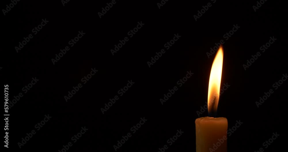 Close-up single candle burning on dark black background, candle fire flame light