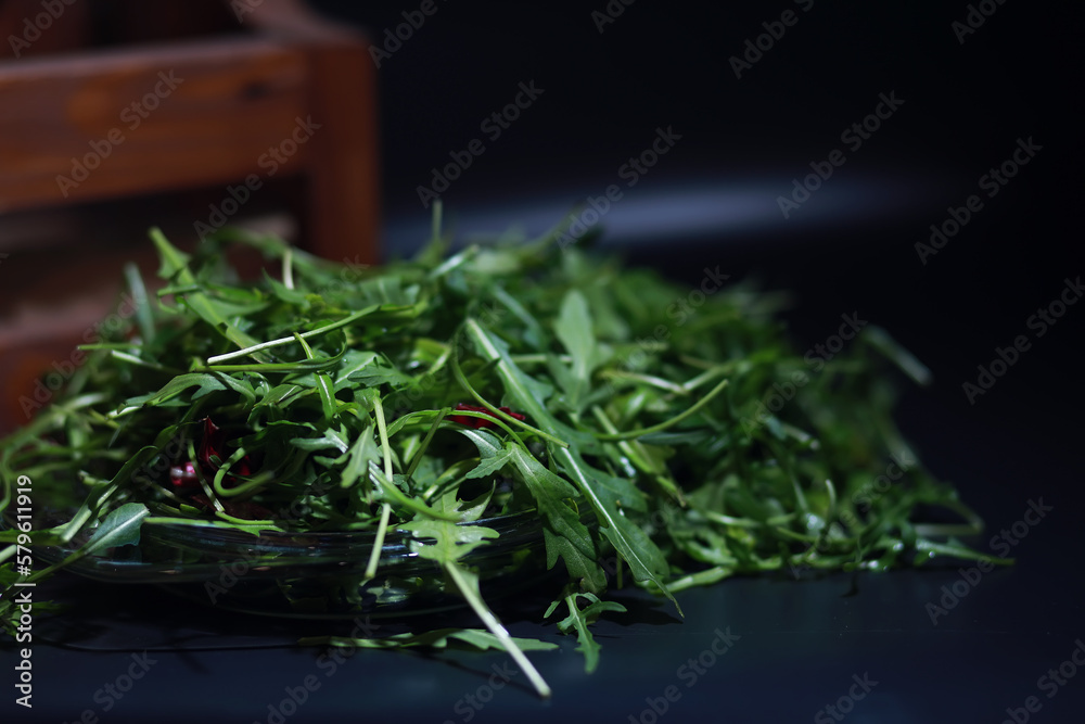 Green vegan salad from green leaves mix and vegetables. Fresh arugula leaves in a colander. Black background.