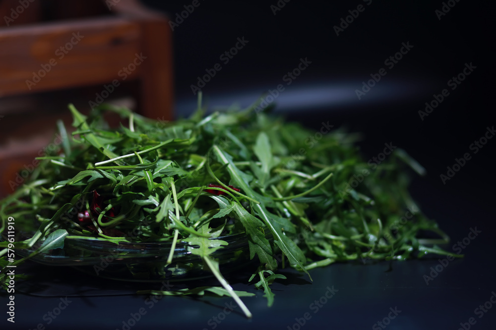 Green vegan salad from green leaves mix and vegetables. Fresh arugula leaves in a colander. Black background. Green vegan salad from green leaves mix and vegetables. Fresh arugula leaves in a colander. Black background.