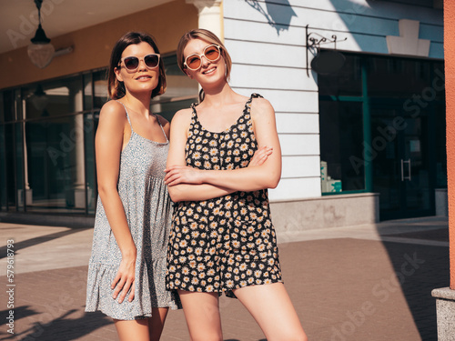 Two young beautiful smiling hipster female in trendy summer dress clothes.Sexy carefree women posing on street background. Positive models having fun, hugging in sunglasses. In sunglasses