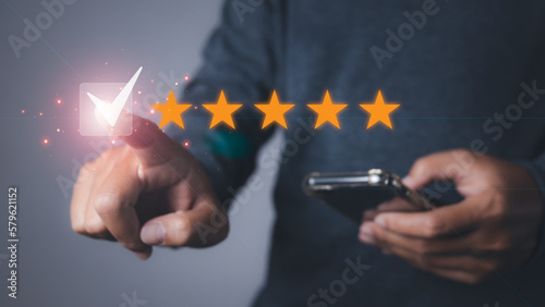 Foto Man using phone giving high score with five star icon and excellent satisfaction service