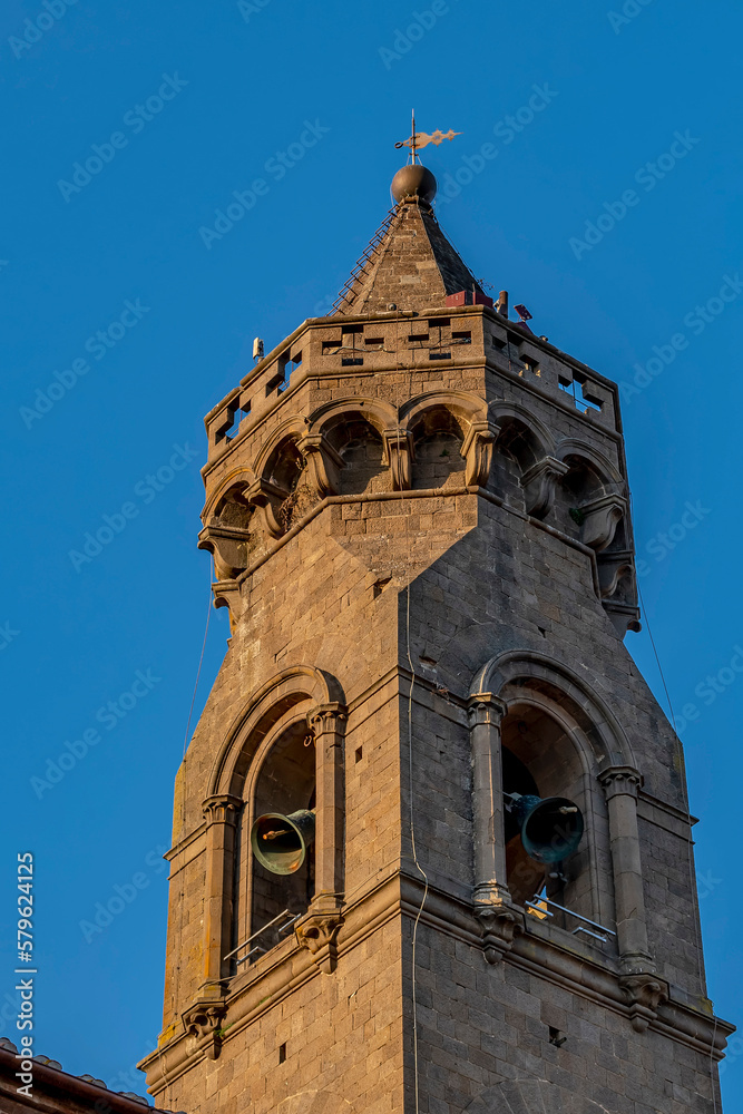 The top of the bell tower of the parish church of San Verano while the bells are ringing, against the blue sky, Peccioli, Pisa, Italy