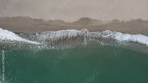 Aerial lookdown of soothing aqua blue sea waves hitting beach sand drone view photo