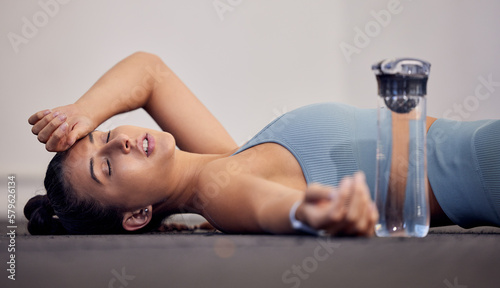 Gym floor, fatigue and woman tired after intense workout, cardio training or yoga fitness exercise. Medical dehydration problem, emergency accident injury and sports athlete faint in pilates studio