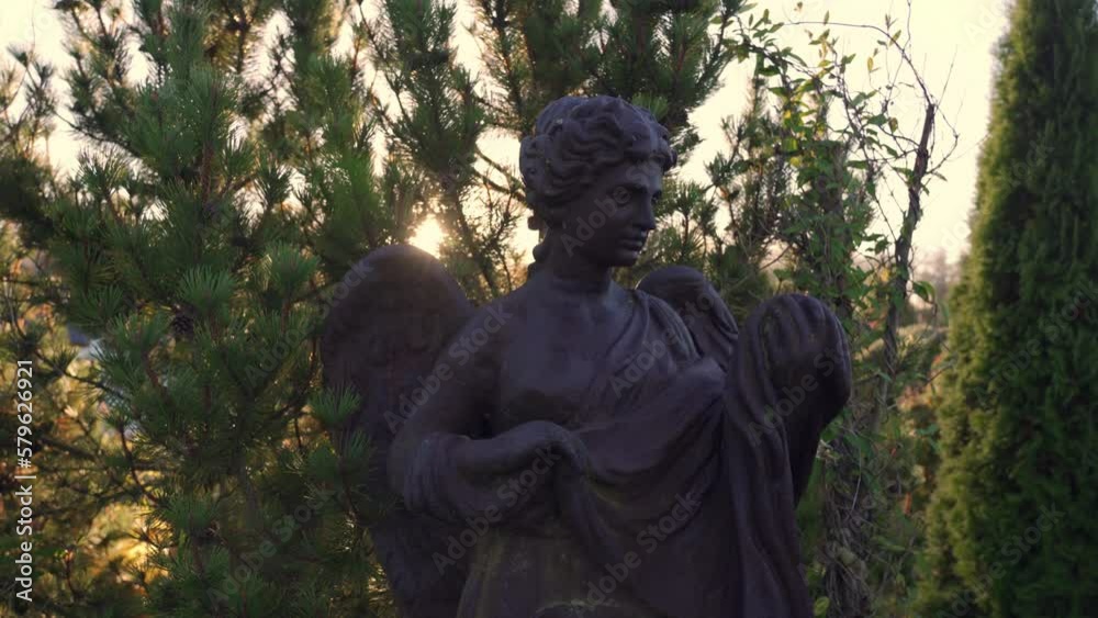 Old rusty statue of an angel on a sunny morning in the cemetery. Camera moves closer to an old iron statue. Old rusty statue of an angel on a sunny morning in the cemetery. Camera moves closer to an old iron statue.