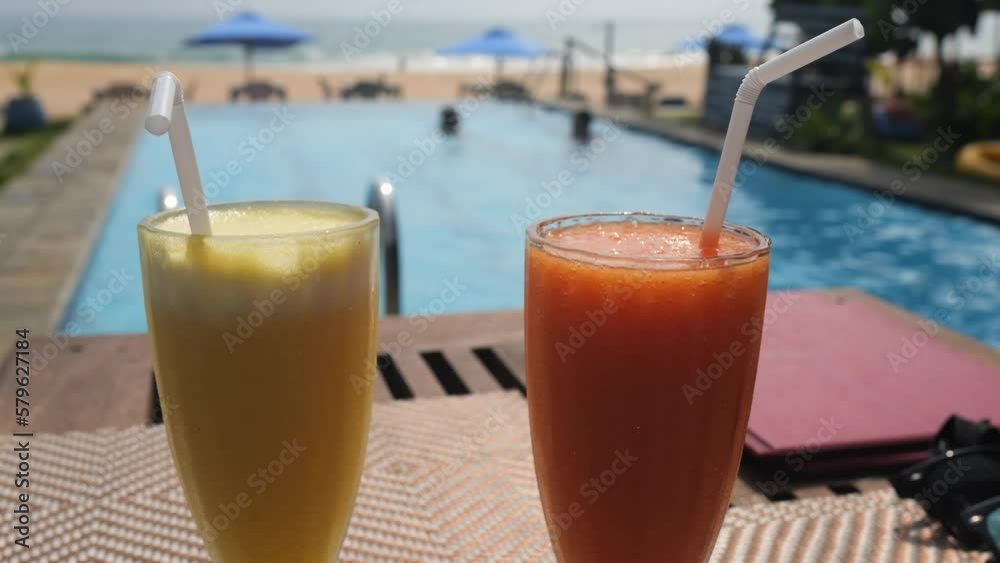 Pineapple and papaya juice in the glass with a swimming pool in the background. Pineapple and papaya juice in the glass with a swimming pool in the background.