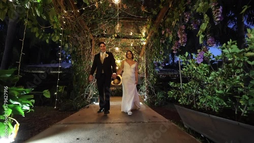 Low angle view of romantic couple looking happy. Man and woman walking with hand in hand to celebrate their wedding day with guests. High quality FullHD footage photo